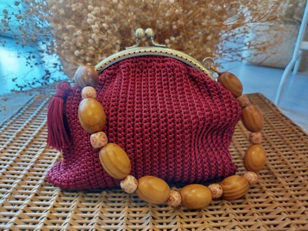 Bolso de ganchillo burdeos con cierre de boquilla dorado y asa de cuentas de madera
